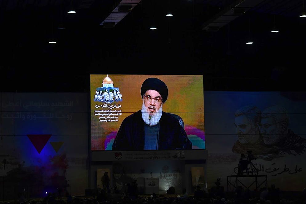 Le persone assistono a un discorso televisivo del segretario generale di Hezbollah Hasan Nasrallah, durante un evento per celebrare il quarto anniversario della morte del comandante iraniano Qasem Soleimani, nel sobborgo meridionale di Beirut, in Libano, il 3 gennaio 2024.