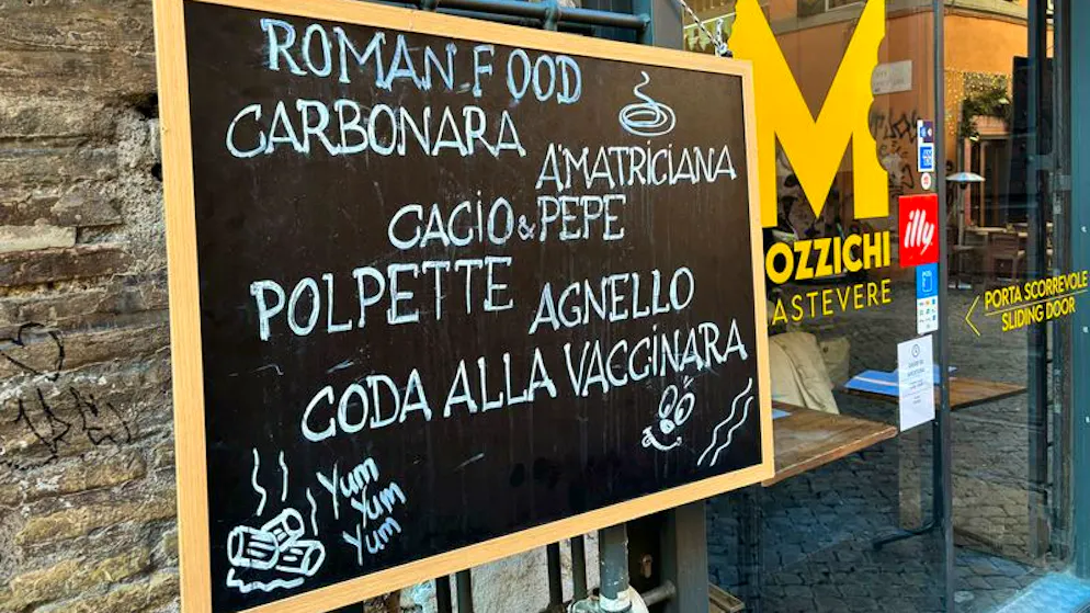 Typisch italienische und römische Speisen stehen auf einer Tafel vor einem Restaurant.