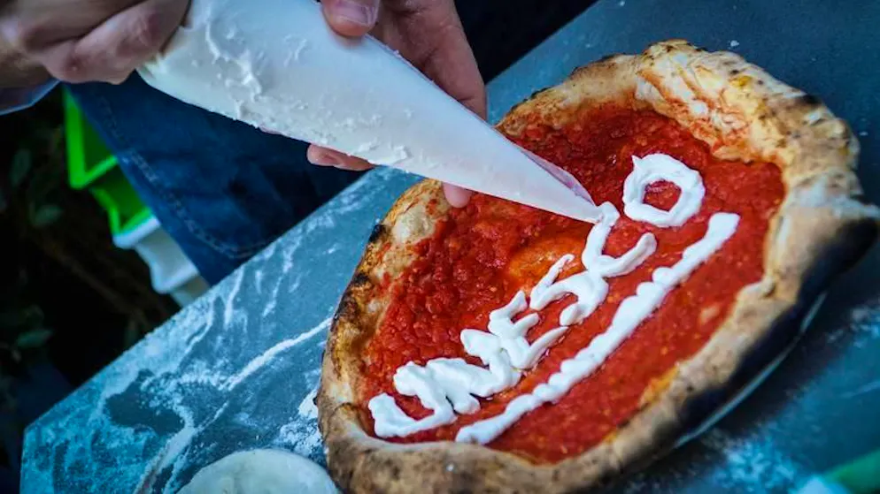 Ein Pizzabäcker schreibt den Schriftzug «Unesco» auf eine Pizza.