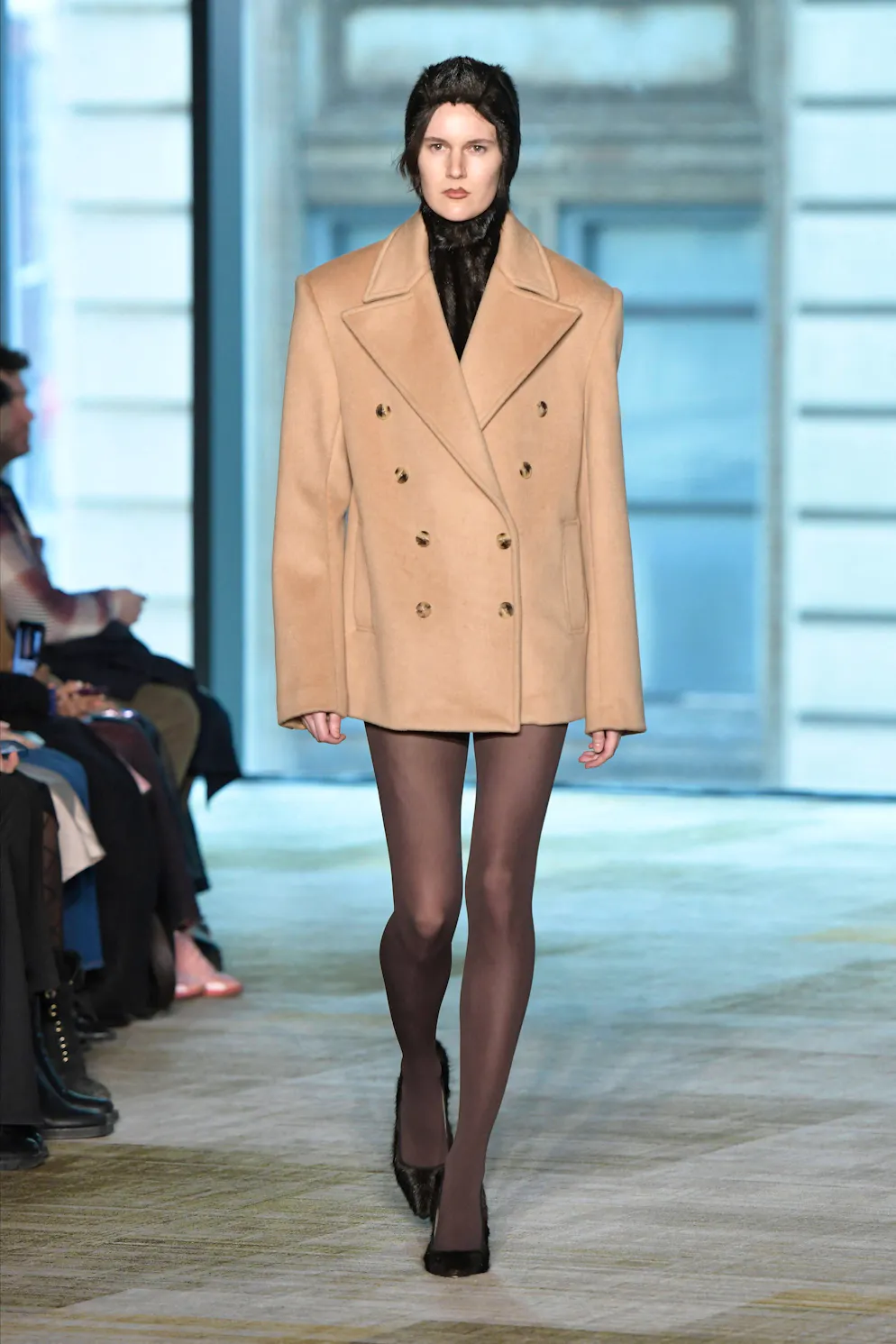 New York Fashion Week: Büro-inspirierter Style. Aknvas kombiniert zur Blazerjacke dunkle Strümpfe und klassische Schuhe. 