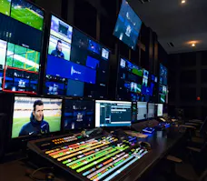 Regiekabine einer Sportübertragung mit zahlreichen Monitoren und Mischpulten für die professionelle Produktion.