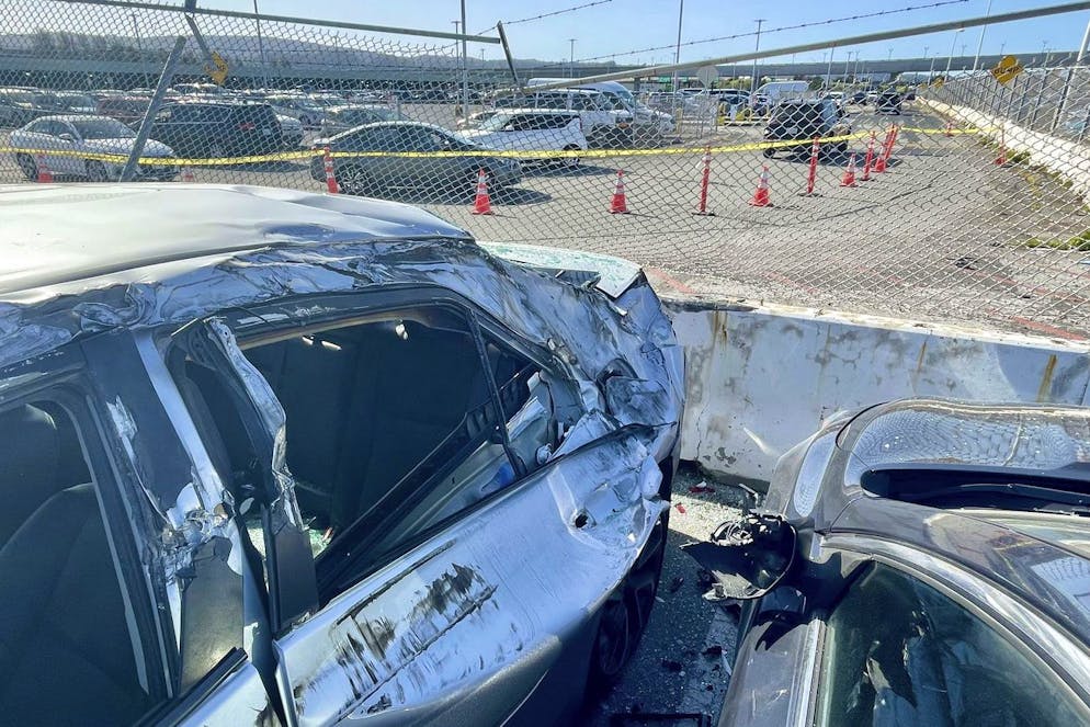 Beschädigte Autos und der kaputte Zaun am Flughafen San Francisco. 