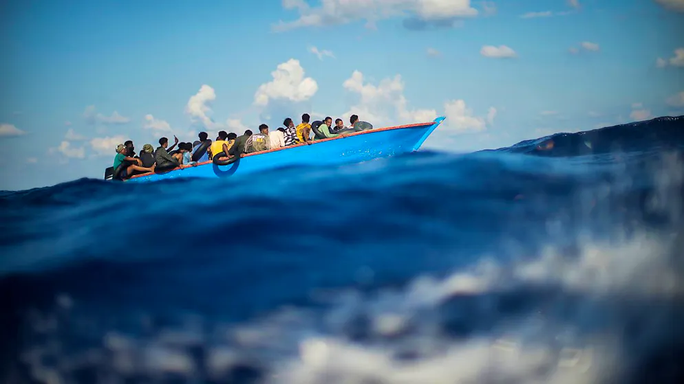 ARCHIV - Migranten sitzen in einem Holzboot im Mittelmeer. Foto: Francisco Seco/AP/dpa