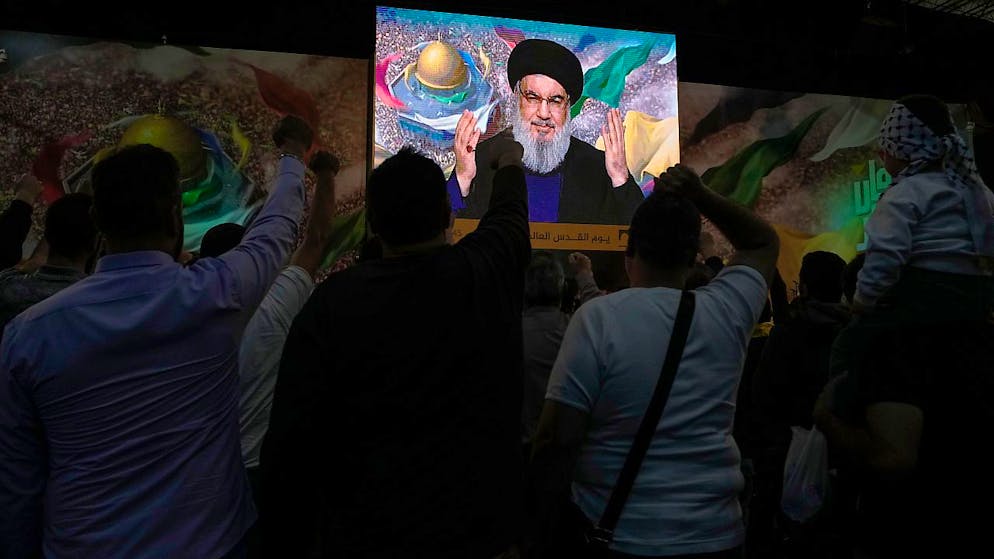 Anhänger der vom Iran unterstützten Hisbollah-Gruppe erheben ihre Fäuste und jubeln, während sie einer Rede des Hisbollah-Führers Hassan Nasrallah zuhören, die dieser über eine Videoverbindung während einer Kundgebung zum Jerusalem-Tag oder Al-Kuds-Tag hält. Foto: Hassan Ammar/AP/dpa
