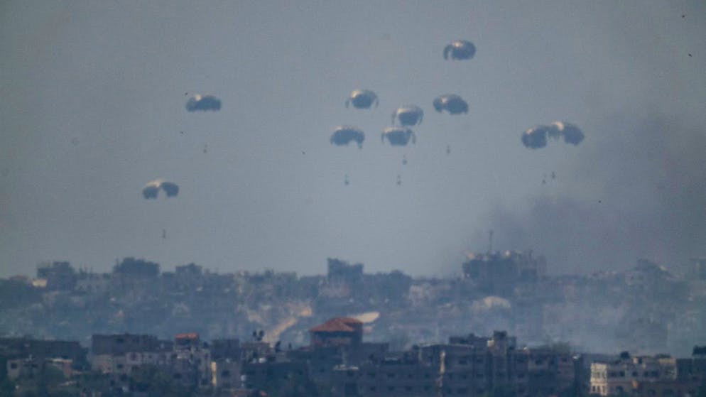 Fallschirme werfen Versorgungsgüter in den nördlichen Gazastreifen ab, vom Süden Israels aus gesehen. Foto: Leo Correa/AP/dpa