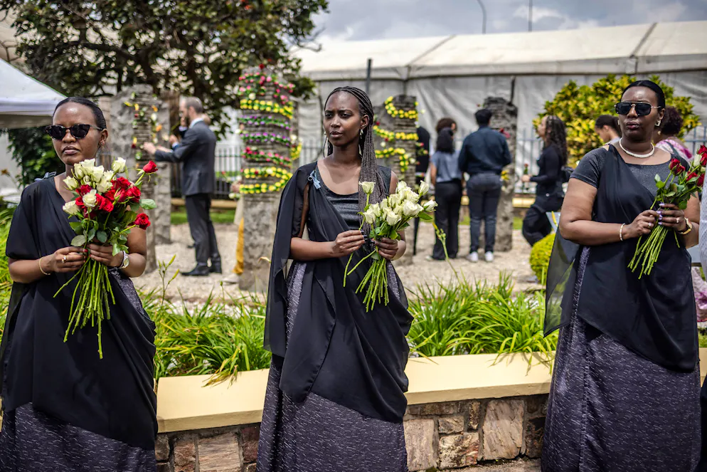 De jeunes Rwandaises tiennent des fleurs devant les colonnes mémorielles en pierre de granit représentant les Casques bleus belges lors de la cérémonie d'hommage aux 10 Casques bleus belges assassinés dans les premières heures du génocide de 1994 contre les Tutsi au Belgian Memorial Camp Kigali à Kigali, le 8 avril 2024, dans le cadre des commémorations du 30e anniversaire du génocide rwandais. (Photo par LUIS TATO / AFP)