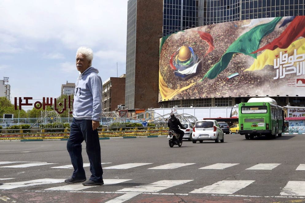 Un uomo iraniano passa davanti a un cartellone anti-israeliano a Teheran.