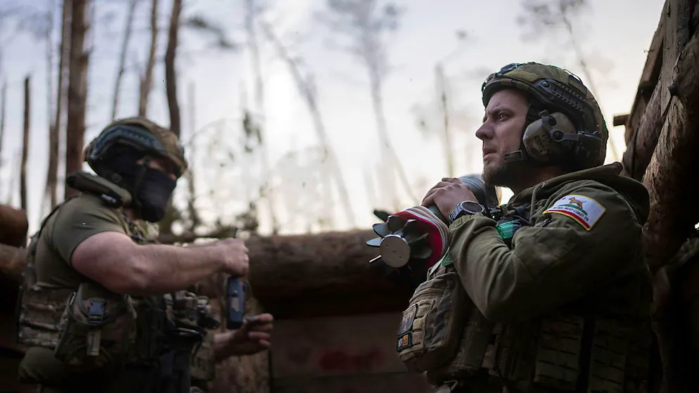 Ein ukrainischer Soldat der Asow-Brigade, bekannt unter dem Rufnamen Chaos, rechts, trägt eine Mörsergranate, während er auf einen Feuerbefehl wartet. Foto: Alex Babenko/AP