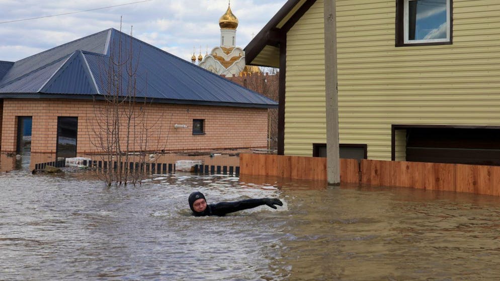 dpatopbilder - Ein Anwohner schwimmt in der überfluteten Straße zwischen Häusern in Orenburg. Foto: Uncredited/AP