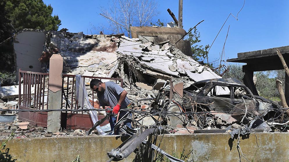 Un électricien libanais répare des câbles électriques devant une maison détruite par une frappe aérienne israélienne, à Alma al-Shaab, un village libanais frontalier avec Israël, dans le sud du Liban, Tsahal répondant à une attaque du Hezbollah.