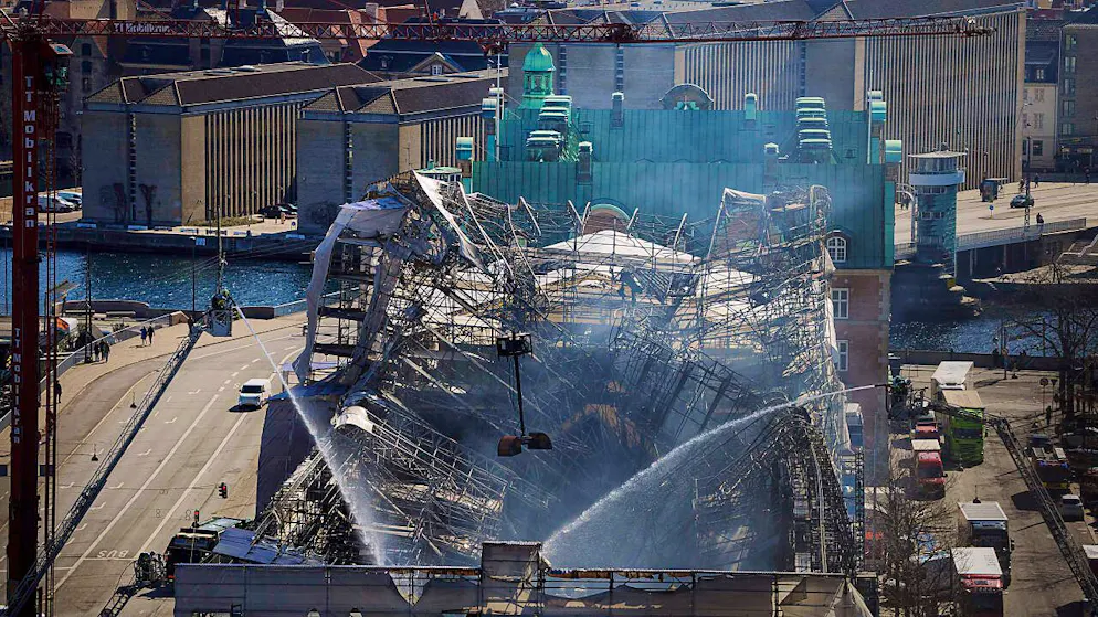 Einsatzkräfte arbeiten daran, das Feuer vollständig zu löschen und das Gebäude der ehemaligen Börse von Kopenhagen zu sichern. Ein Feuer wütete am Vortag in dem Bau, einem der ältesten Gebäude Kopenhagens, und verursachte den Einsturz des ikonischen Turms der Alten Börse aus dem 17. Jahrhundert. Foto: Liselotte Sabroe/Ritzau Scanpix Foto/AP/dpa