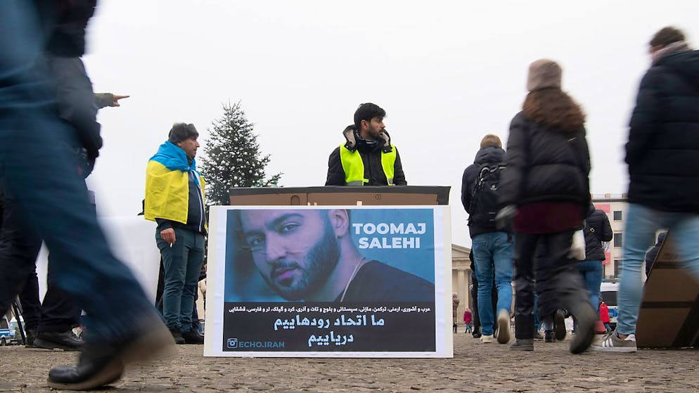 ARCHIV - Ein großes Plakat steht bei einer Protestaktion gegen Irans Staatsführung auf dem Pariser Platz. Es zeigt den iranischen Rapper Toomaj Salehi. Foto: Paul Zinken/dpa