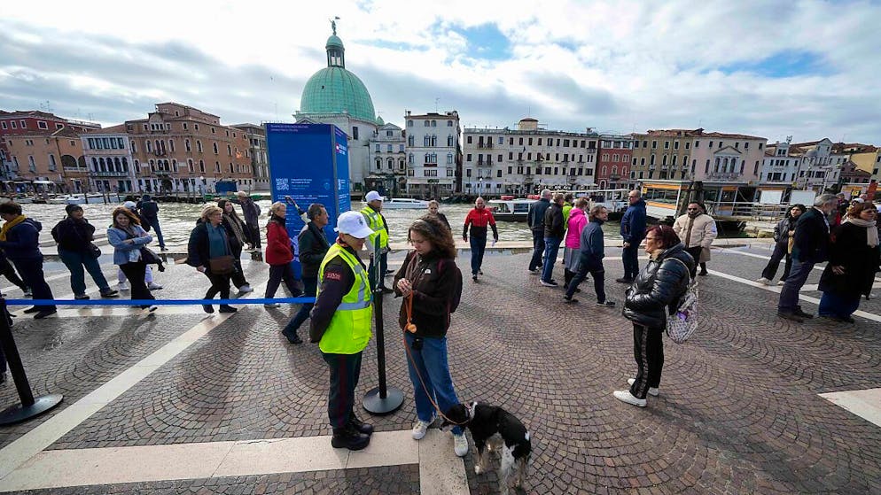 Kontrolleure überprüfen den QR-Code der Touristen vor dem Hauptbahnhof. Foto: Luca Bruno/AP/dpa