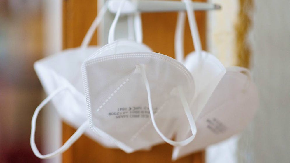 ARCHIV - FFP2-Masken hängen an einer Türklinke. Foto: Daniel Karmann/dpa