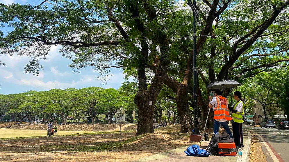 Arbeiter schützen sich in Quezon City auf den Philippinen mit einem Schirm vor der extremen Hitze. Foto: Girlie Linao/dpa