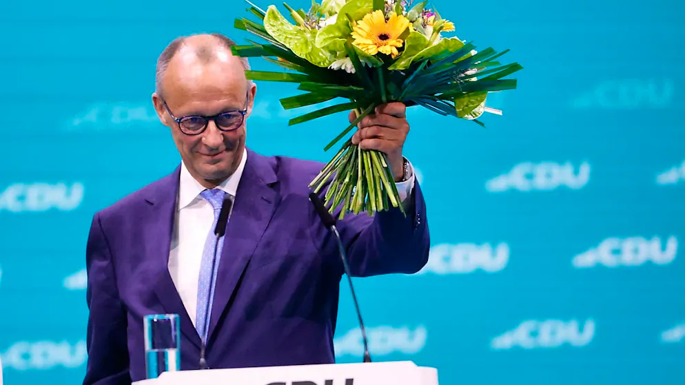 Friedrich Merz, CDU-Bundesvorsitzender, hält seinen Blumenstrauß nach der Wahl zum Bundesvorsitzenden beim CDU-Bundesparteitag hoch. Foto: Carsten Koall/dpa