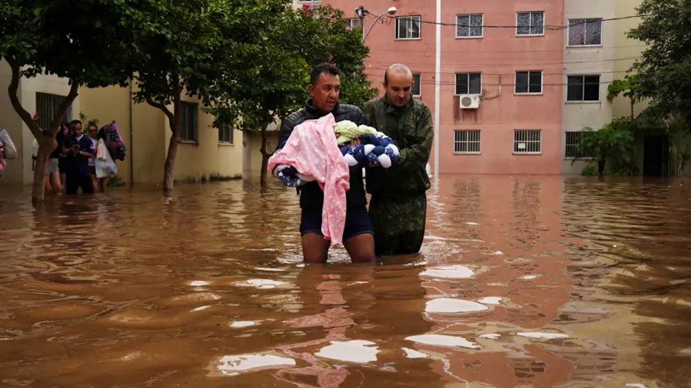 dpatopbilder - Männer waten durch eine überschwemmte Straße im brasilianischen Canoas. Foto: Carlos Macedo/AP