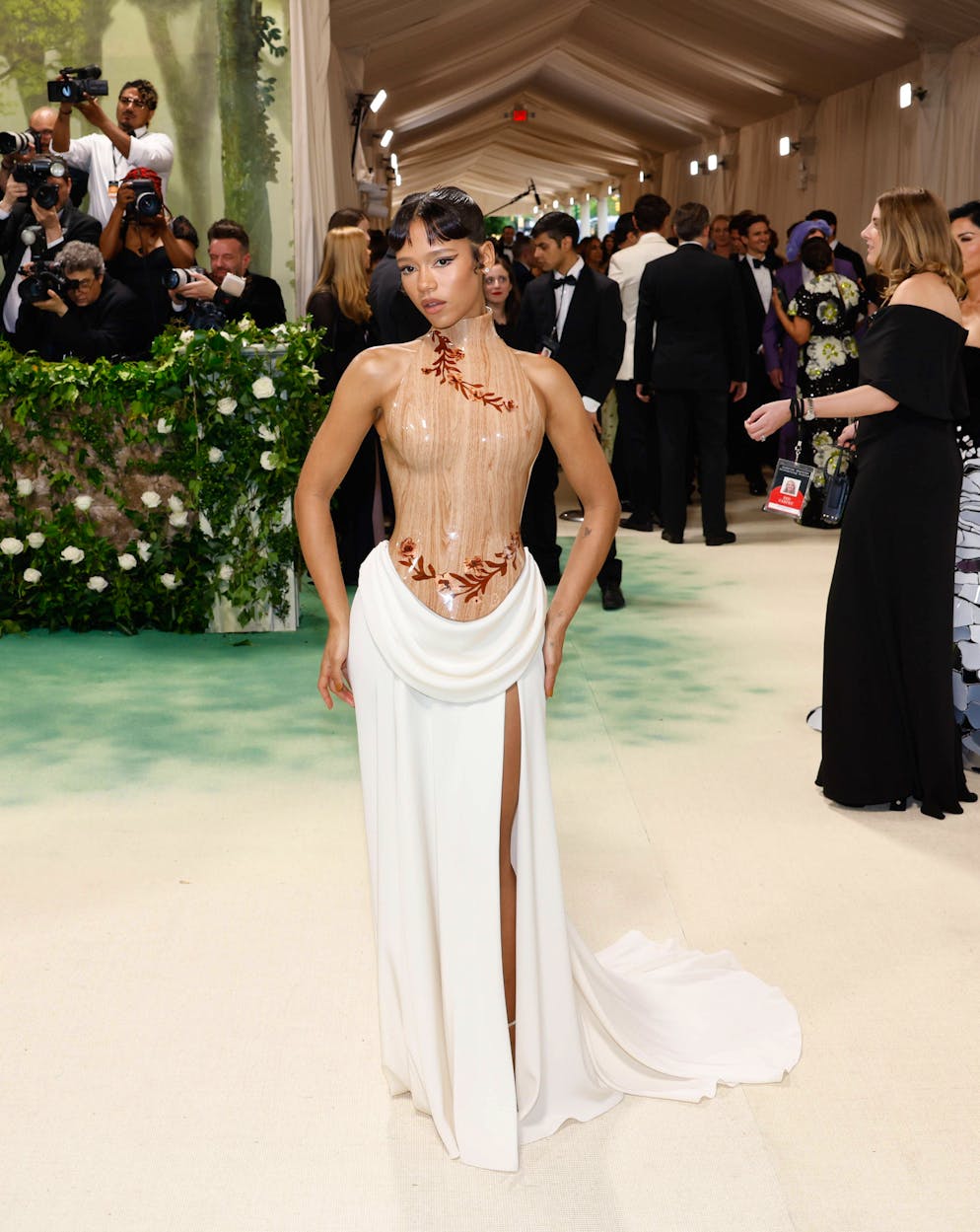 Die aufregendsten Looks der Met Gala. Hölzerne Angelegenheit bei Taylor Russell: Die Schauspielerin entschied sich für eine Kombination von Loewe, bestehend aus einem Korsett-Oberteil und weissem Rock mit Schlitz.
