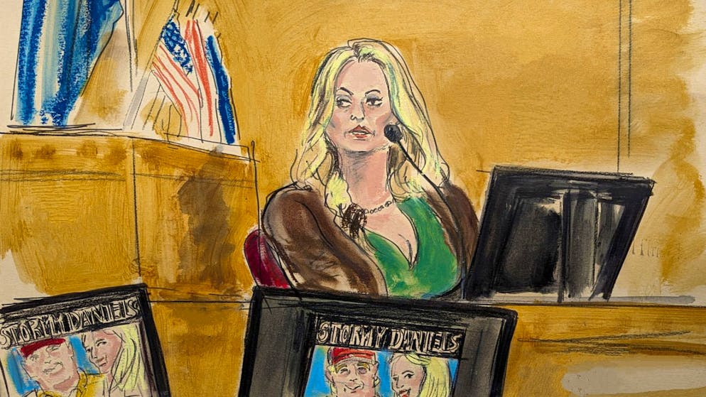 Auf dieser Gerichtszeichnung sagt Stormy Daniels im Zeugenstand aus, während ein Werbebild für eine ihrer Shows auf Monitoren angezeigt wird. Foto: Elizabeth Williams/AP/dpa