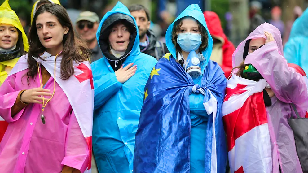 Demonstranten, die georgische National- und EU-Fahnen tragen, stehen vor einer Absperrung der Polizei während eines Protestes der Opposition gegen das «Russische Gesetz» in der Nähe des Parlamentsgebäudes. Foto: Zurab Tsertsvadze/AP/dpa