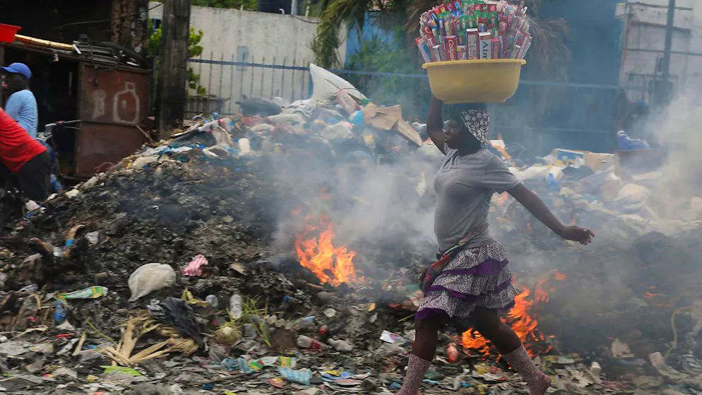 ARCHIV - Eine Person geht in Port-au-Prince, Haiti, an einem Haufen brennender Abfälle vorbei. Foto: Odelyn Joseph/AP/dpa