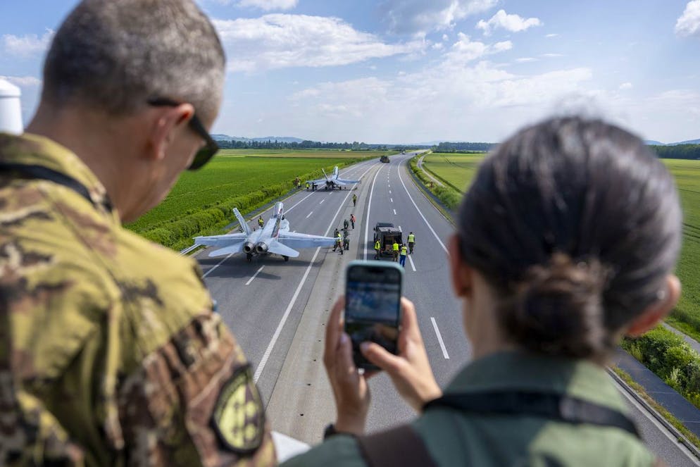 Persone fotografano aerei da combattimento F/A-18 sul tratto autostradale della A1 durante l'esercitazione dell'esercito Alpha Uno, mercoledì 5 giugno 2024, sul tratto autostradale della A1 a Payerne. Non si tratta di uno show ma di un'esercitazione, ecco perchö solo 300 persone hanno potuto seguire l'evento sul posto. Molti di loro erano esperti del settore.