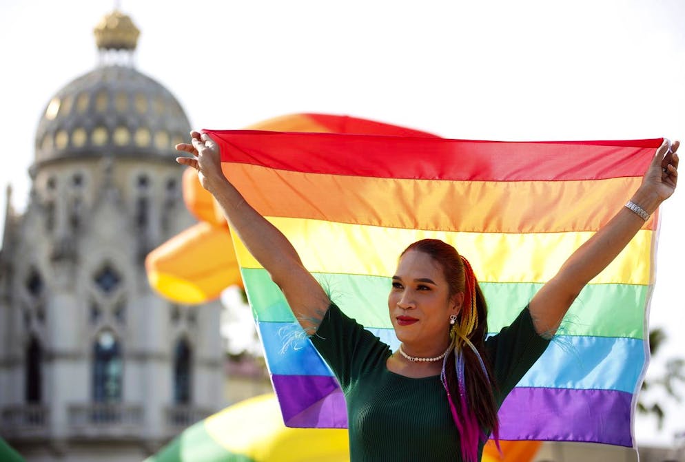 Una donna thailandese festeggia con una bandiera arcobaleno l'approvazione della legge sull'uguaglianza matrimoniale da parte del Senato durante una cerimonia ufficiale presso la Government House di Bangkok, in Thailandia, il 18 giugno 2024.