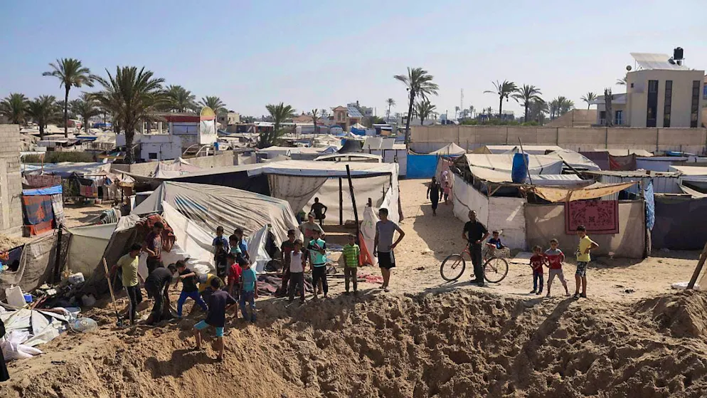 Palestinians gather at the edge of a crater after an Israeli airstrike in an area where displaced people have taken refuge in the southern Gaza Strip. Photo: Jehad Alshrafi/AP
