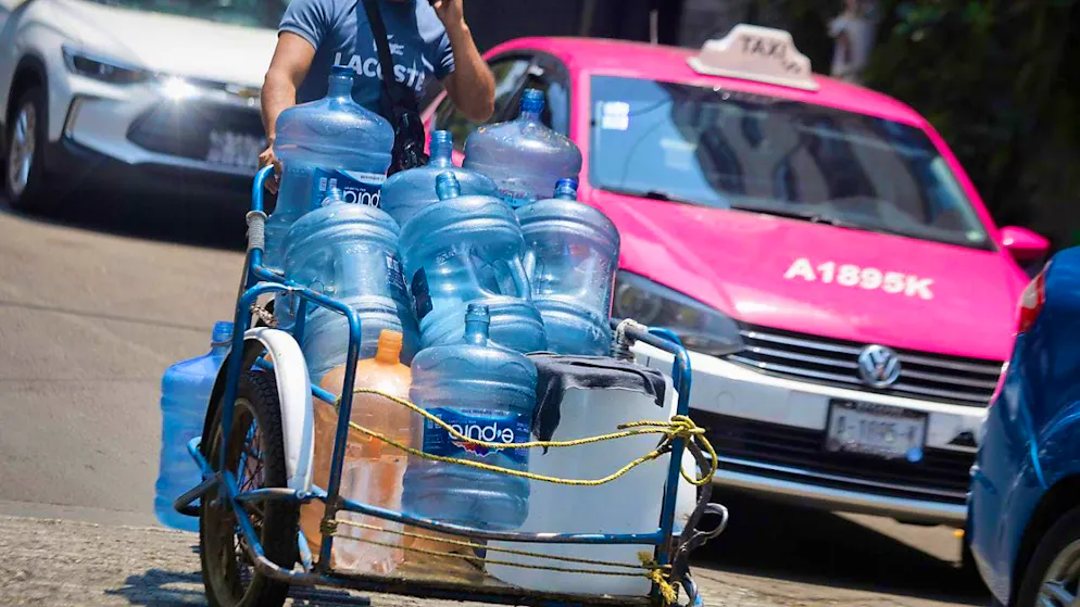 A man walks through the street with empty water canisters on a very hot day. Photo: Gerardo Vieyra/dpa