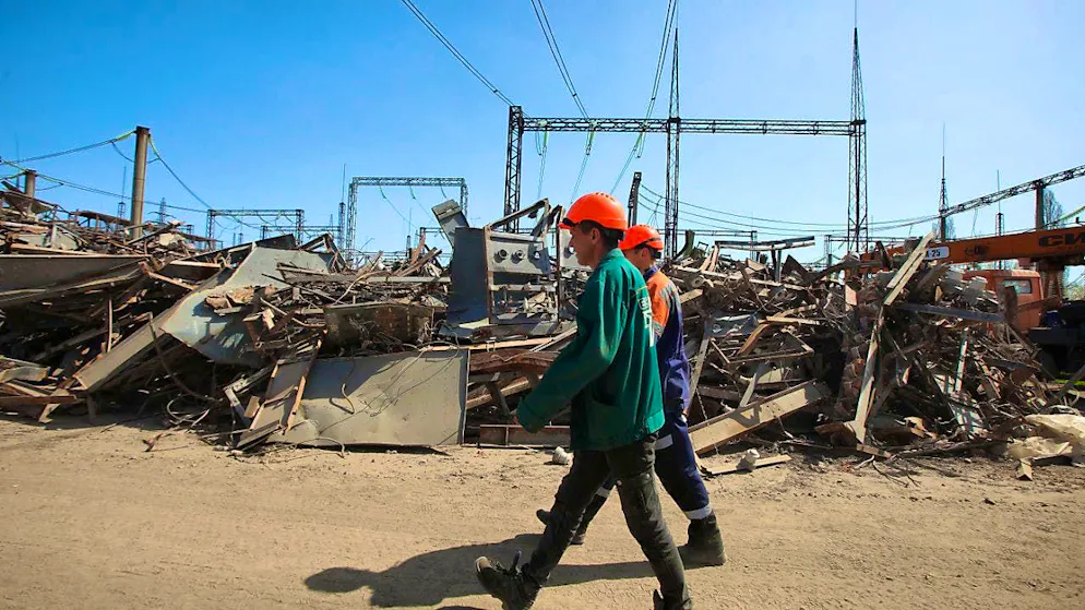 ARCHIVE - Utility workers walk past the rubble of a power plant damaged by Russian shelling. Photo: -/Ukrinform/dpa