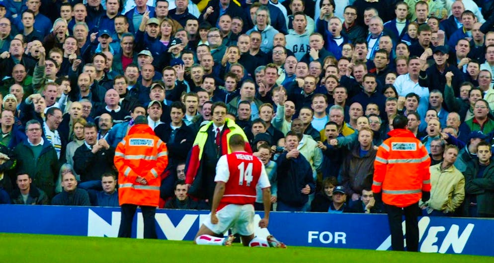 Thierry Henry kneels on the pitch in front of the opposing fans.