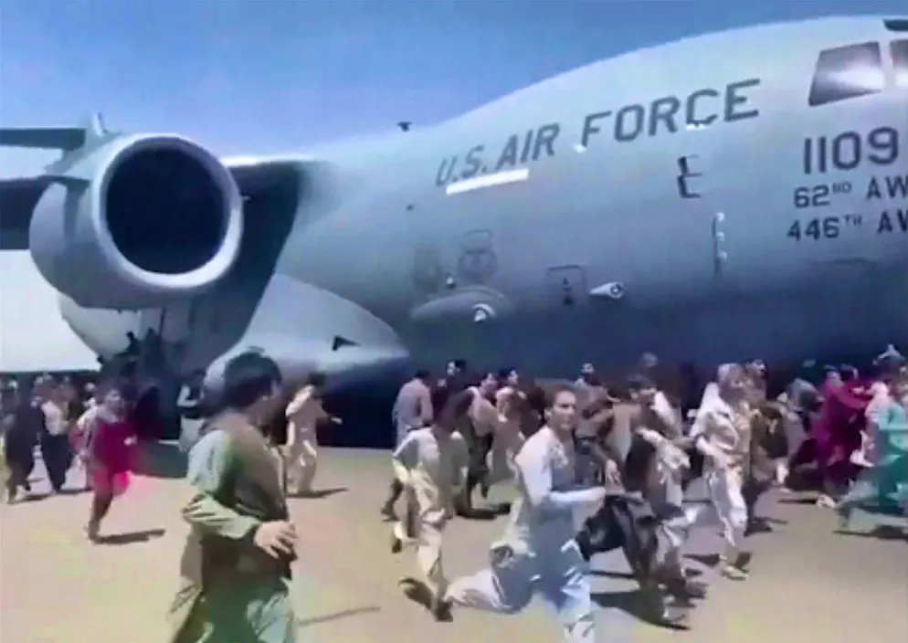 August 16, 2021: Desperate Afghans run along the runway next to a US C-17 transport plane.