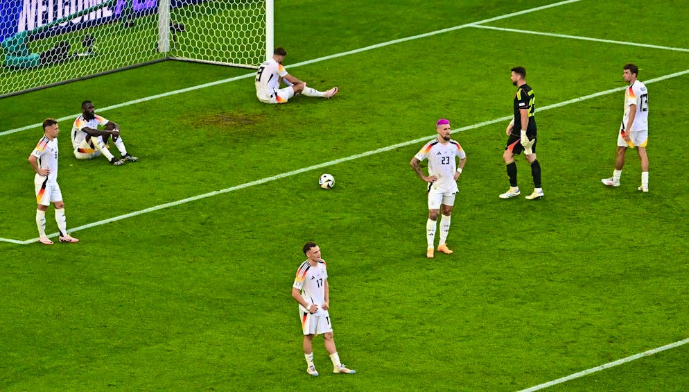 The German players stand disappointed on the pitch after the final whistle.