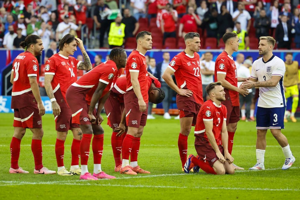 Switzerland's Ricardo Rodriguez, Steven Zuber, Denis Zakaria, Granit Xhaka, Manuel Akanji, Fabian Schaer, Silvan Widmer and Vincent Sierro, from left, react next to England's Luke Shaw, right, after losing the penalty shoot-out of the quarter final match between England and Switzerland at the Euro 2024 soccer tournament in Duesseldorf, Germany, Saturday, July 6, 2024. (KEYSTONE/Peter Klaunzer)