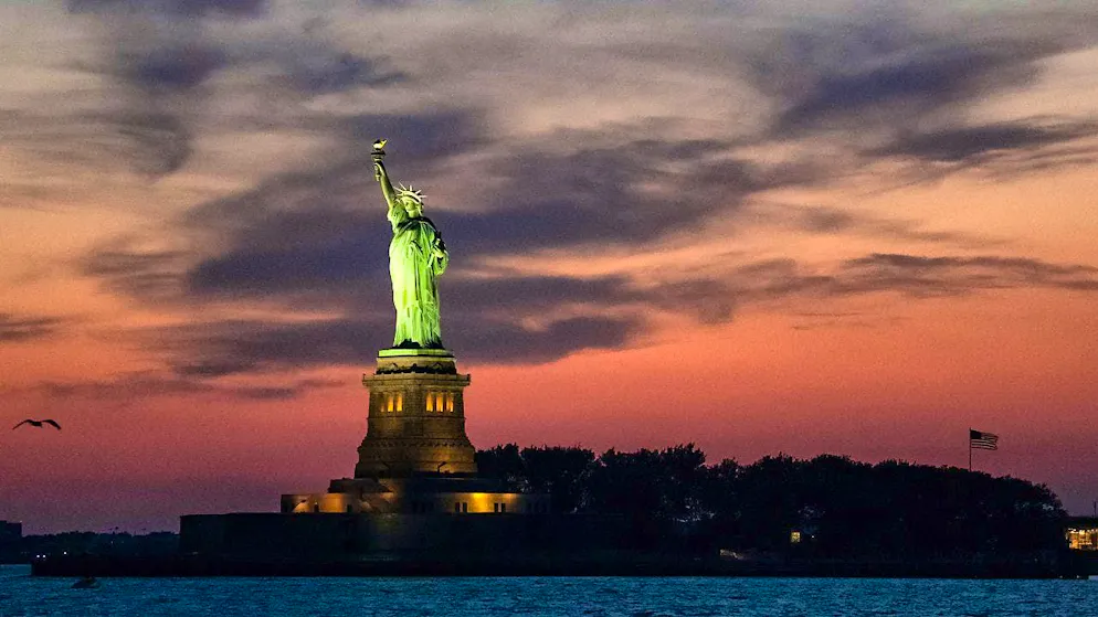 The Statue of Liberty is illuminated at dusk.