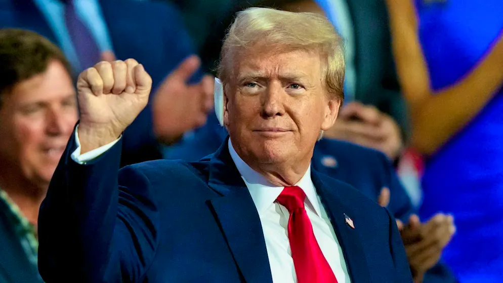 Trump raises his fist in the air at the party convention and is cheered by delegates in the convention hall.