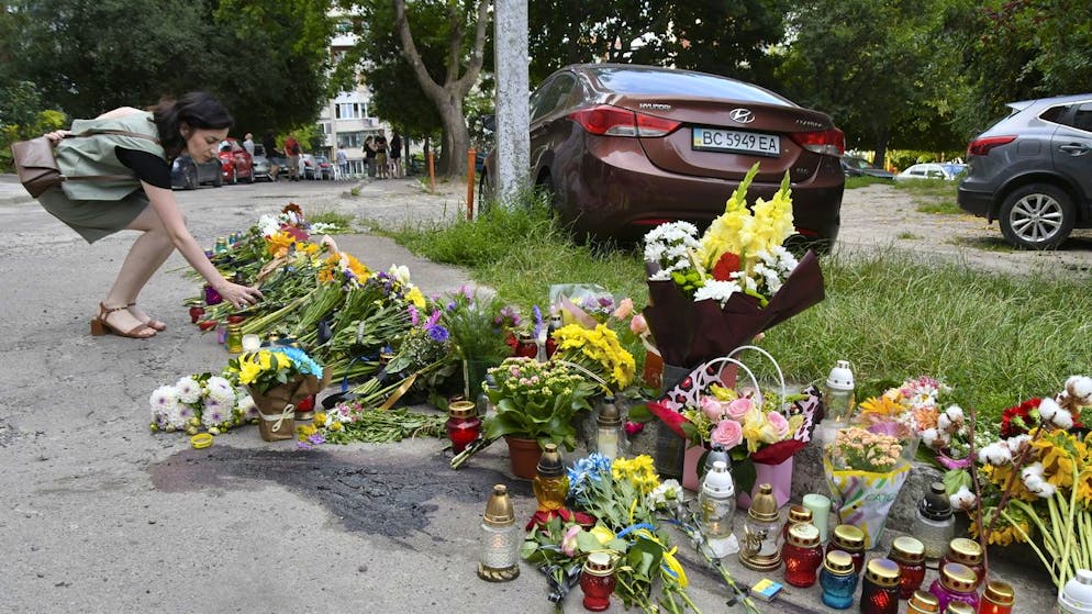 Menschen legen in Lwiw Blumen am Ort der tödlichen Schussabgabe ab.