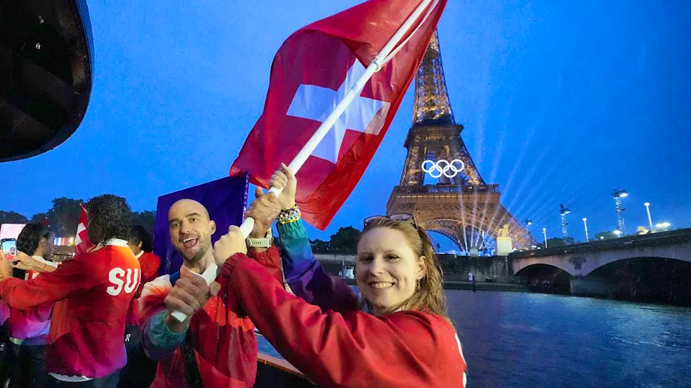 Olympic Games in Paris open with parade on the Seine - Gallery. Nina Christen and Nino Schurter wave the national flag on the Swiss boat