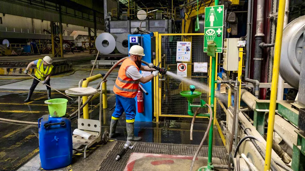 Two Novelis employees clean the mud between the machines on the site in Sierre (picture from July 11).