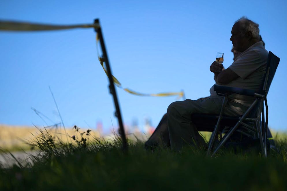 Une personne boit un verre de vin rose assis sur une chaise a l'ombre du soleil ce dimanche 28 juin 2015 a Sarzens, Vaud. (KEYSTONE/Laurent Gillieron)
