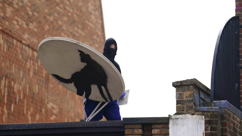 Un uomo incappucciato si porta via l'opera, solo pochi istanti dopo essere stata svelata al pubblico.