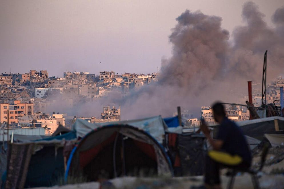 Il fumo si alza a seguito di un attacco aereo israeliano mentre i palestinesi sfollati siedono accanto alle loro tende nel campo di Khan Younis, nel sud della Striscia di Gaza, 13 agosto 2024 (immagine d'illustrazione).