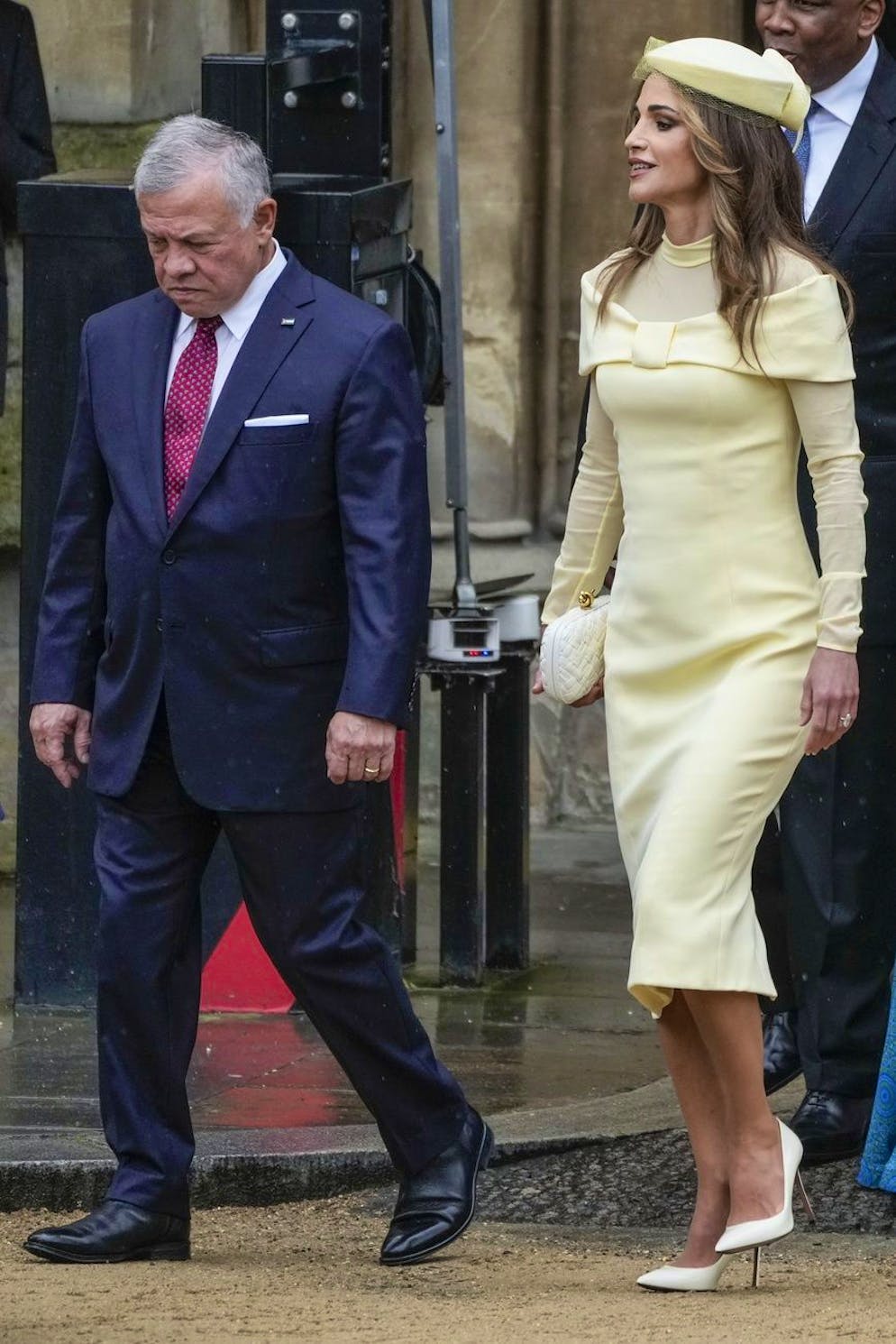 La reine Rania de Jordanie, mamie stylée. Clutch et bibi ssorti à sa robe midi jaune pâle pour la cérémonie du couronnement du roi Charles III, le 6 mai 2023. La reine Rania n'a aucun mal à adapter ses tenues à ses sorties.