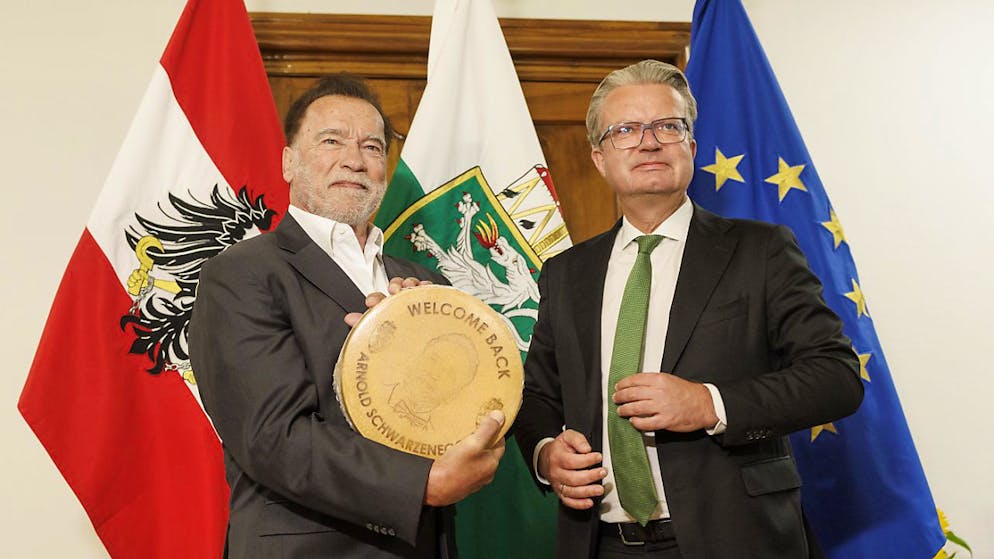 Arnold Schwarzenegger (l) bekommt einen Käse vom Landeshauptmann der Steiermark, Christopher Drexler (ÖVP) anlässlich der Präsentation einer Büste von Alt-Landeshauptmann Josef Krainer. Foto: Erwin Scheriau/APA/dpa