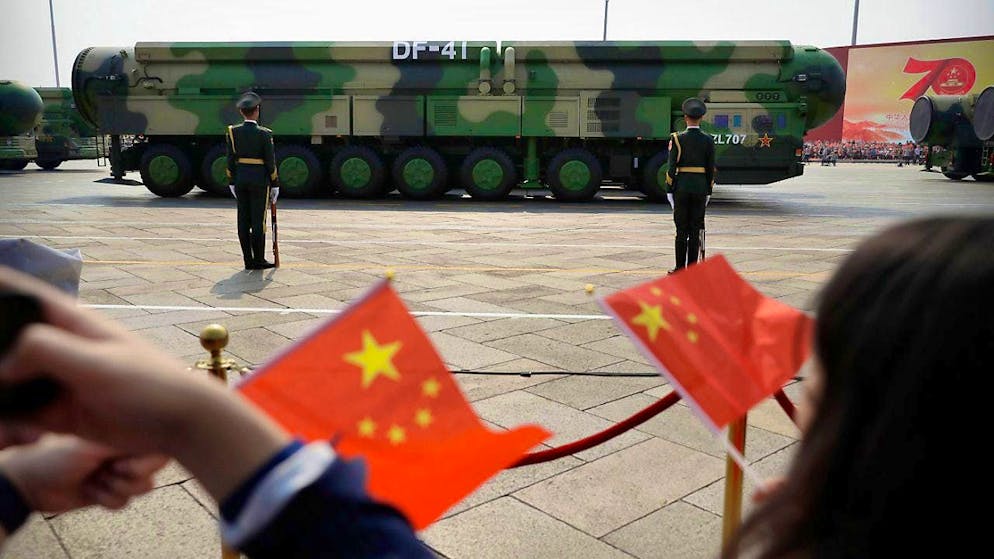 ARCHIVE - Spectators wave Chinese flags as military vehicles carrying DF-41 nuclear missiles drive past during a parade (archive photo). Photo: Mark Schiefelbein/AP/dpa
