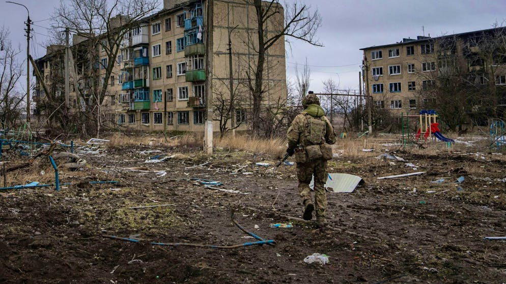 A Ukrainian marine walks past destroyed apartment blocks in Wuhledar.