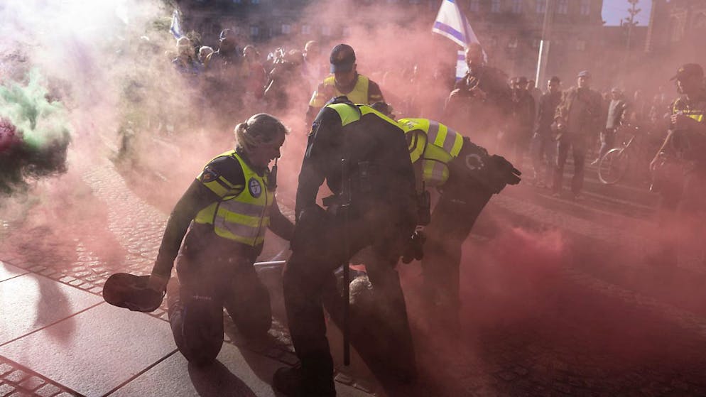 Ein pro-palästinensischer Demonstrant mit einer Rauchbombe wird in Amsterdam von der Polizei festgehalten. Foto: Peter Dejong/AP