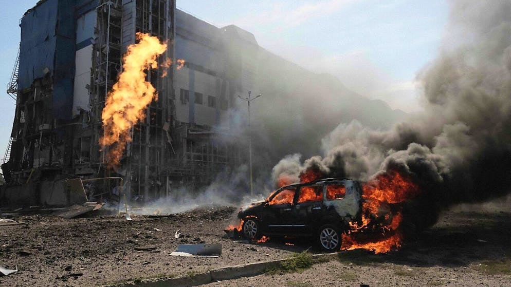 dpatopbilder - ARCHIV - Ein brenndes Auto in Charkiw vor einem Geschäftszentrum, das durch russische Angriffe beschädigt wurde. Foto: George Ivanchenko/AP/dpa
