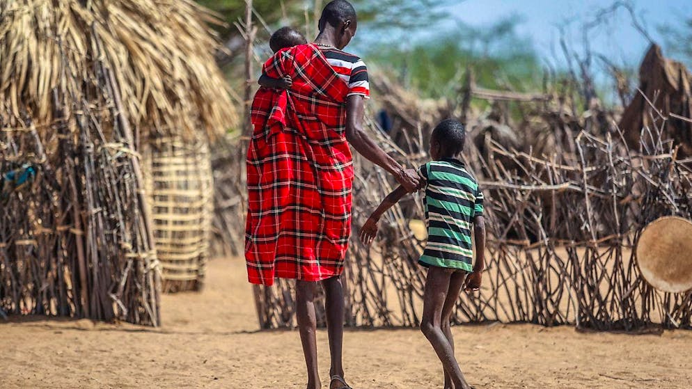 A father helps his malnourished son walk near their hut in the village of Lomoputh in northern Kenya.