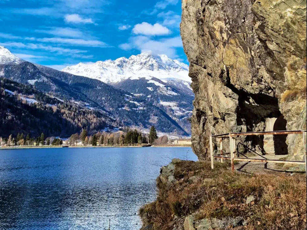 Tornando verso nord, prima di entrare in una delle due gallerie le quali rendono unico il percorso attorno al lago di Poschiavo, in alto si possono ammirare le cime che fanno da cornice al passo del Bernina. 